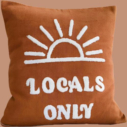 Brown pillow with white sun and 'Locals Only' text on a beige background