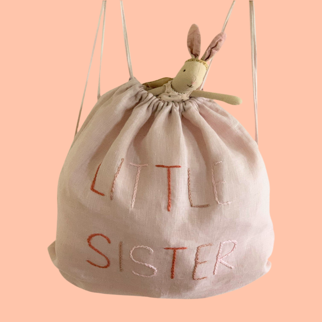 Drawstring bag with 'LITTLE SISTER' text .