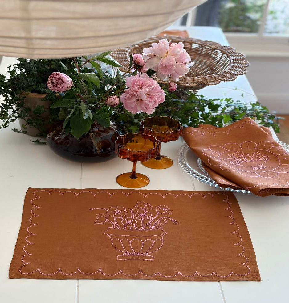Decorative tan linen with pink embroidery placemat with floral design on a table with flowers and glasses Jane paquin - bowden x littlenordic sol collaboration 