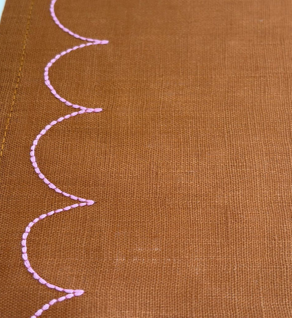 tan fabric with pink scallop embroidery stitching detail