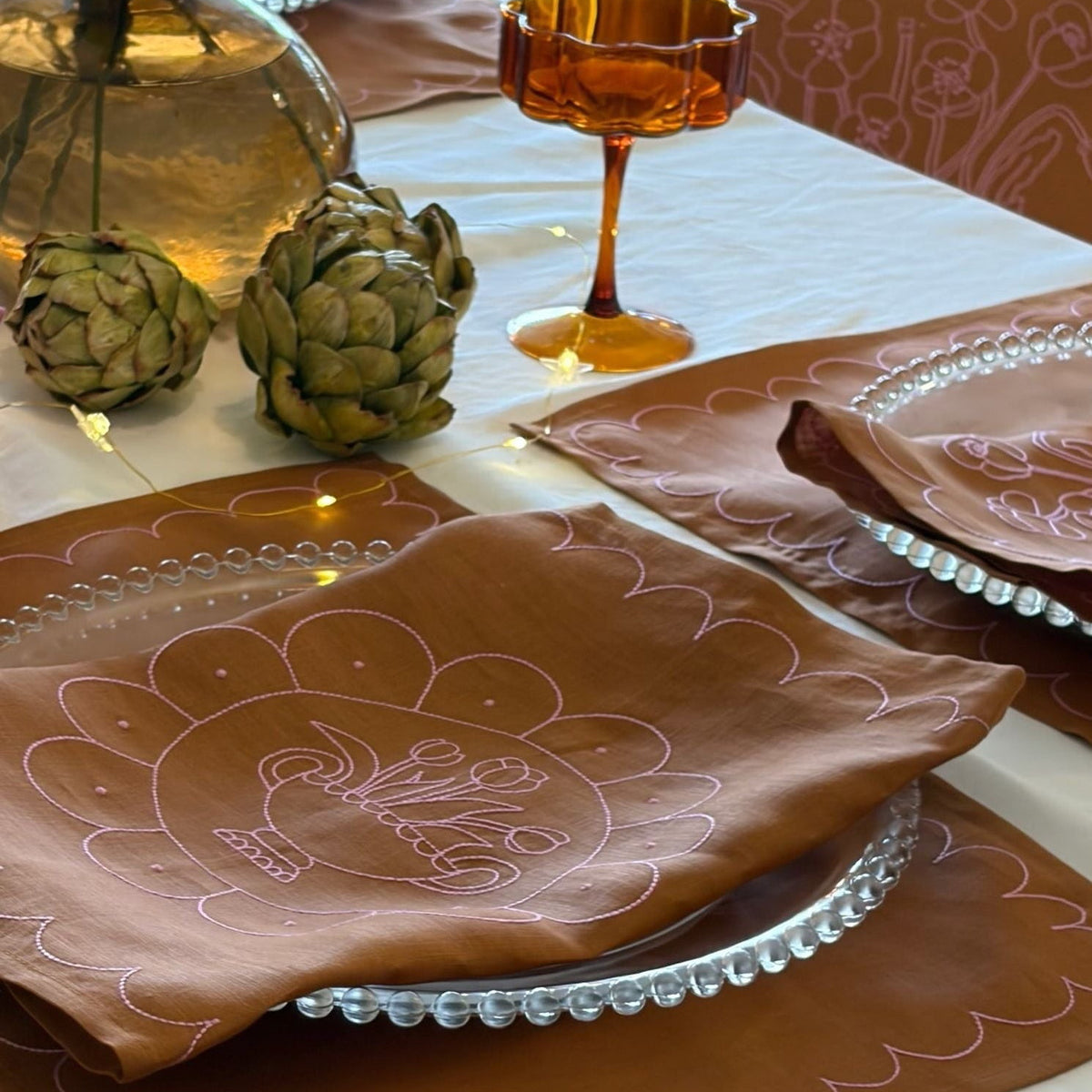 Decorative table setting with brown napkins featuring a turkey design on a white tablecloth.