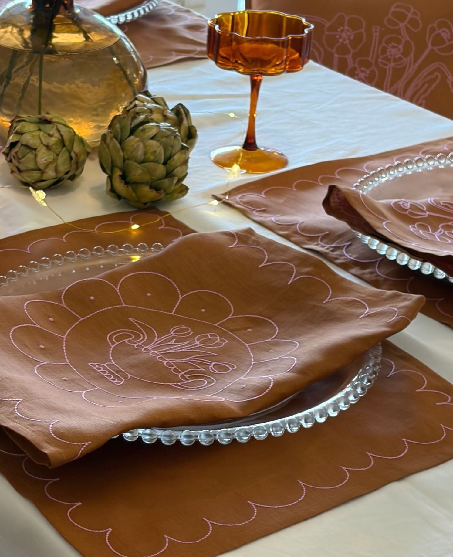 Decorative table setting with brown napkins featuring a turkey design on a white tablecloth.