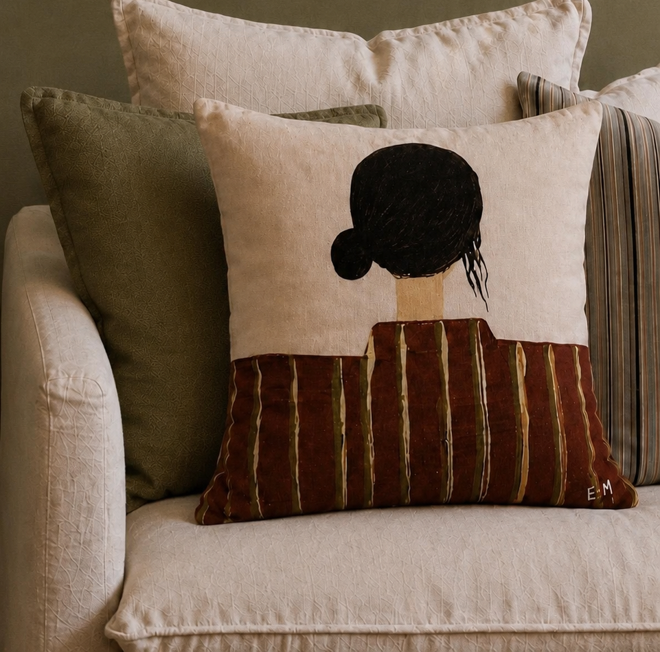 Little Nordic Sol Olive cushion back view with illustrated dark hair and striped design styled on a neutral armchair