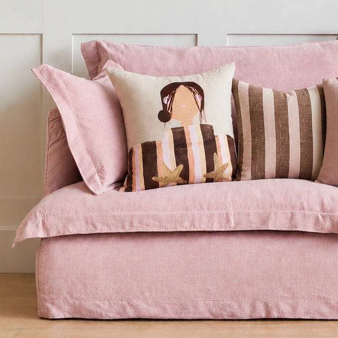 Little Nordic Sol Sadie cushion with illustrated girl and gold star details styled on a soft pink bed