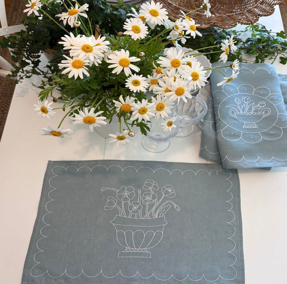 Bouquet of white flowers with yellow centres  on a table with decorative blue and white linen placemats.