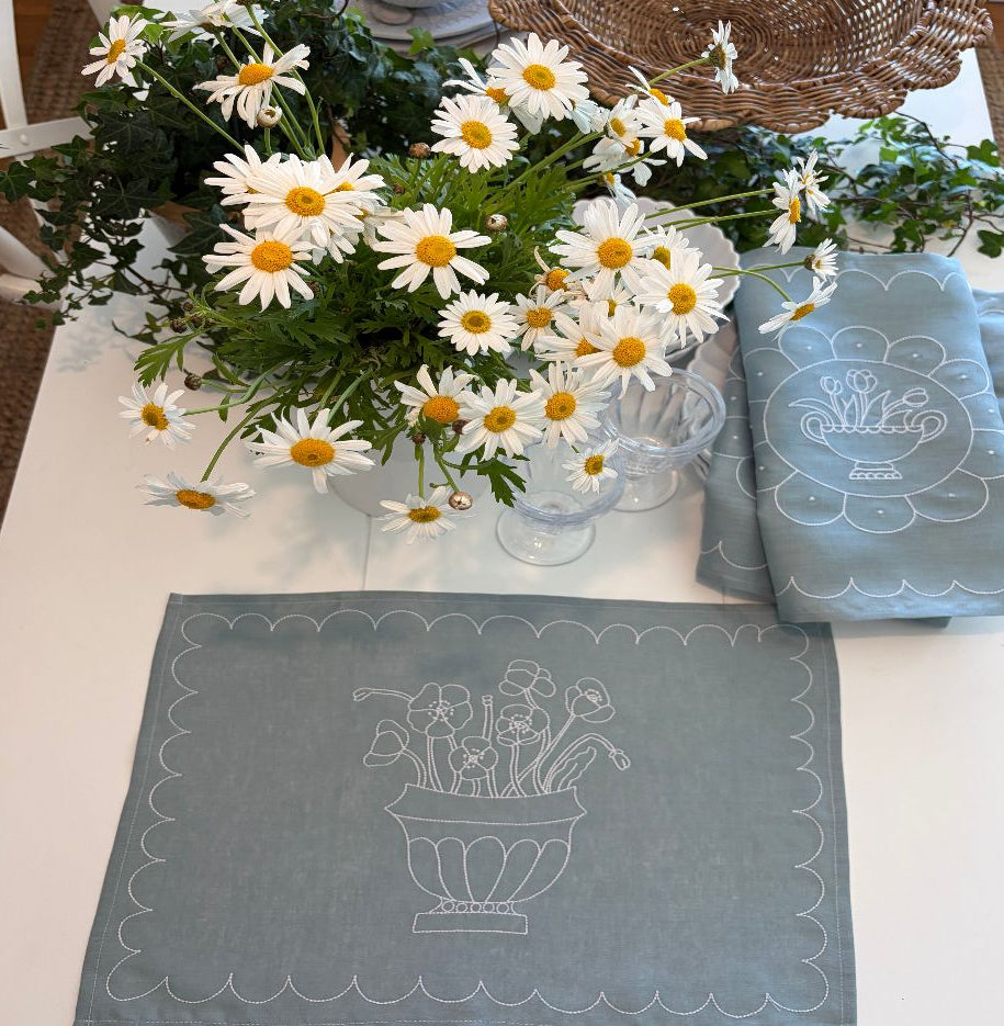 Bouquet of white flowers with yellow centres  on a table with decorative blue and white linen placemats.