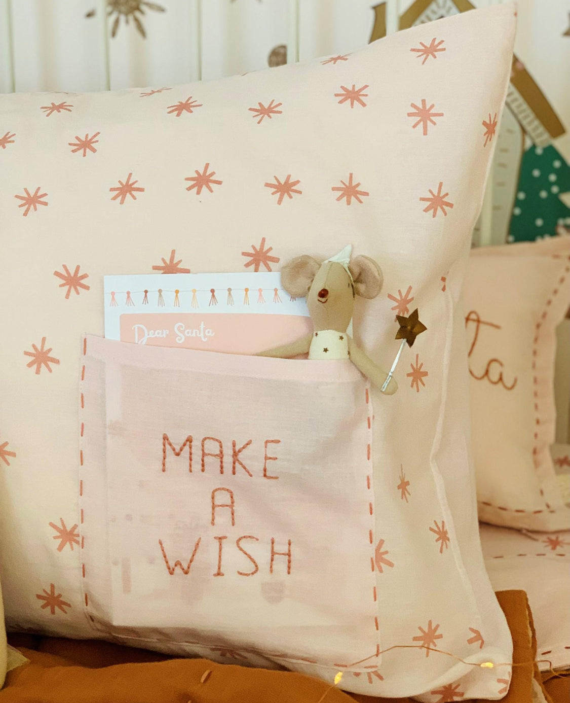 Decorative pillow with 'MAKE A WISH' text and a small plush toy inside.