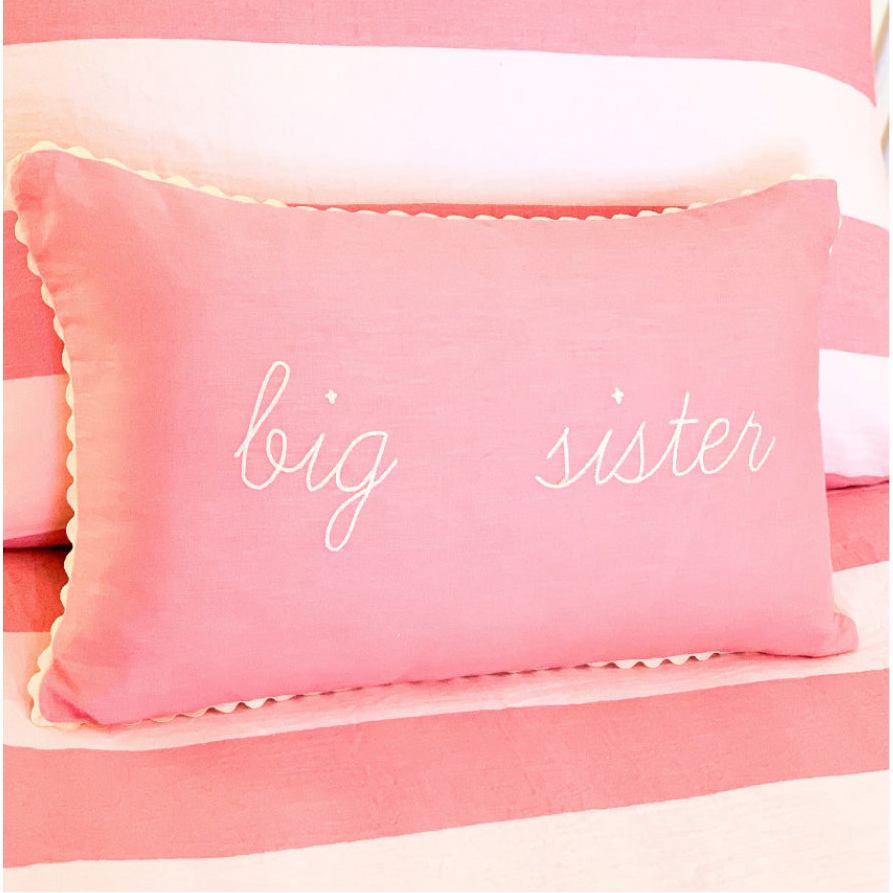Pink pillow with 'big sister' text on a matching pink background