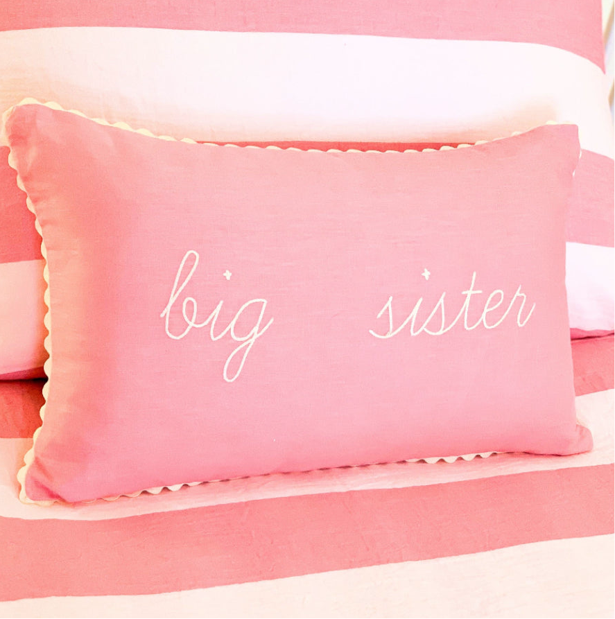 Pink pillow with 'big sister' text on a matching pink background