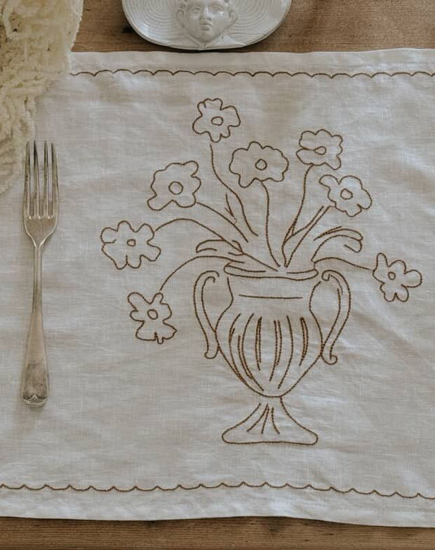 Embroidered tablecloth with floral design on a wooden table.