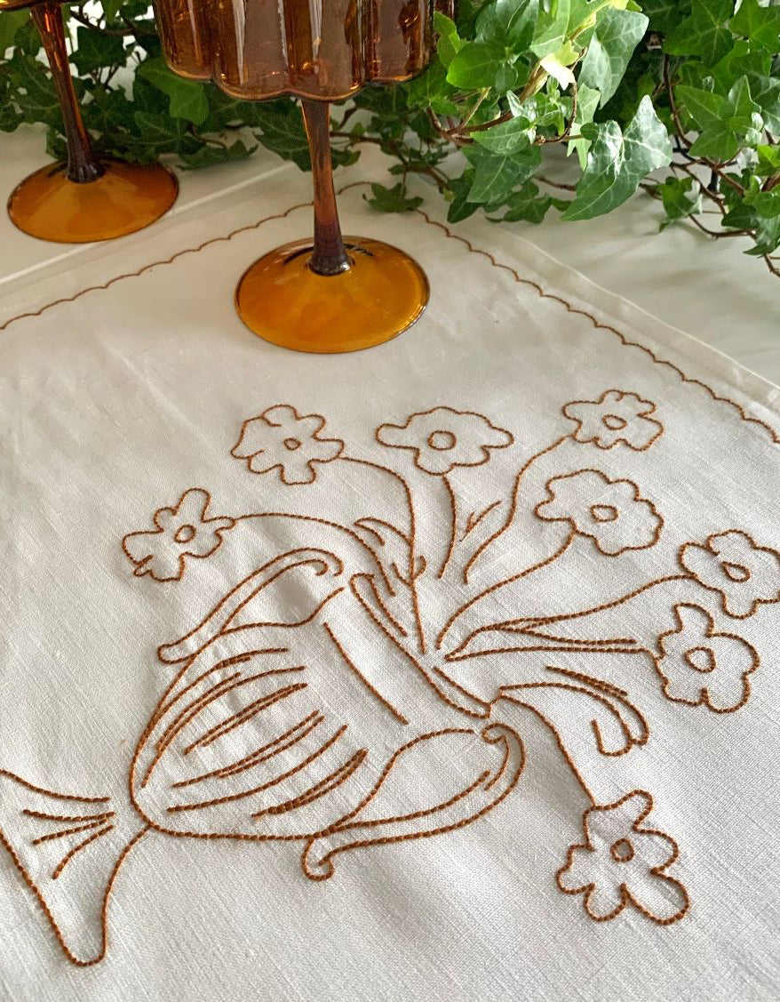 Embroidered tablecloth with floral design on a white background