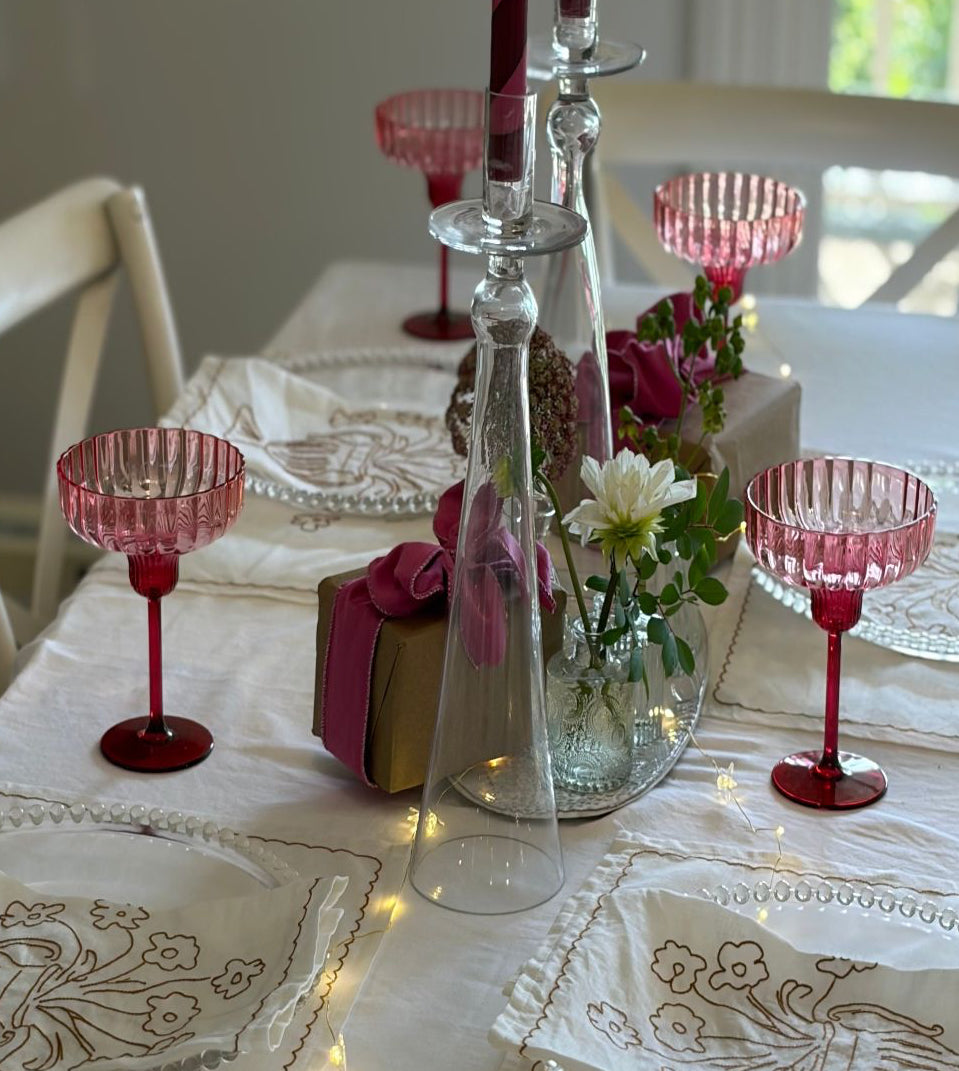 Decorative table setting with red glassware and floral arrangements.