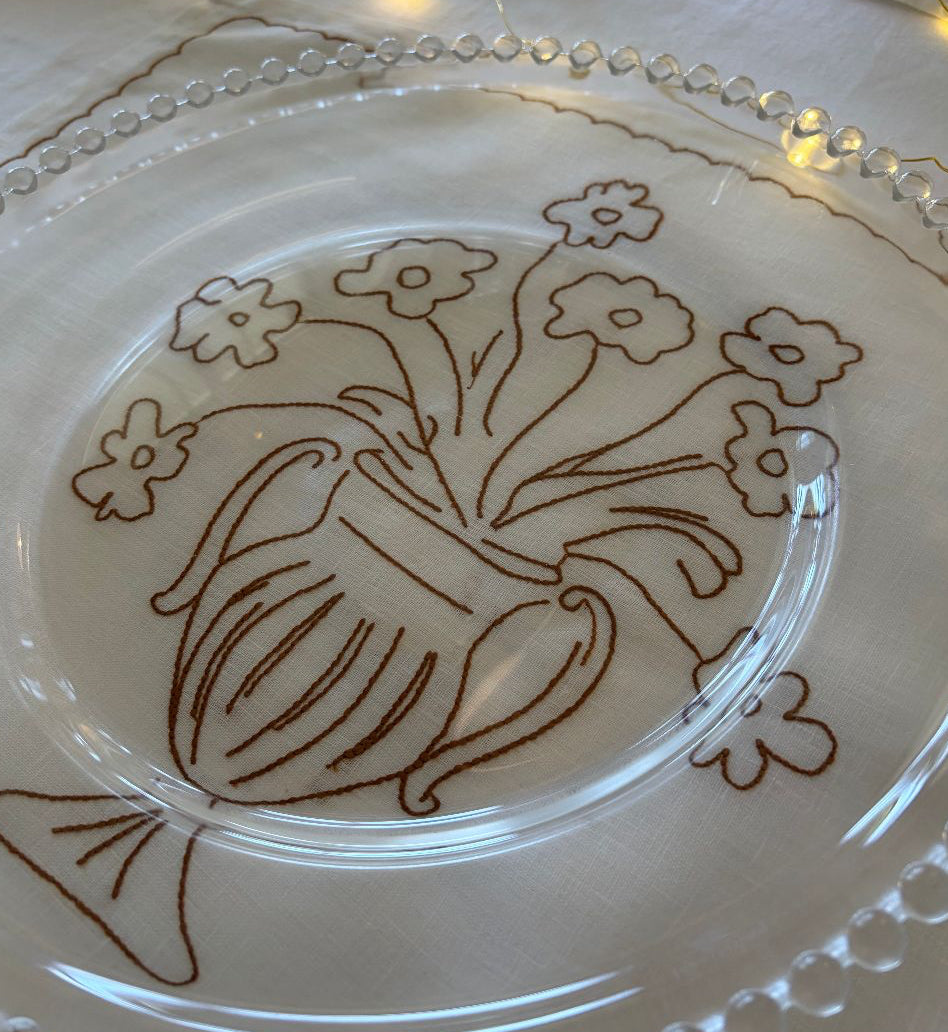 Clear glass plate with brown floral design on a white background
