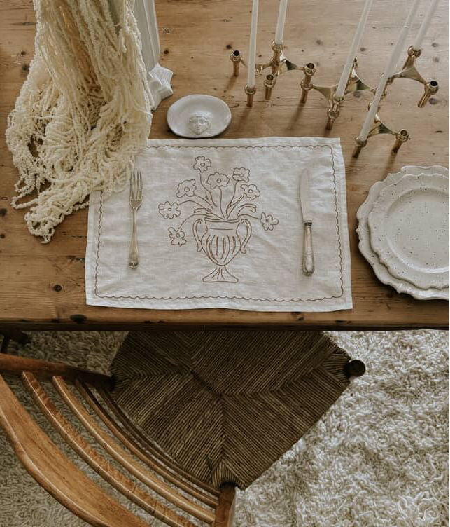 Elegant table setting with a decorative placemat featuring a floral design on a wooden table.