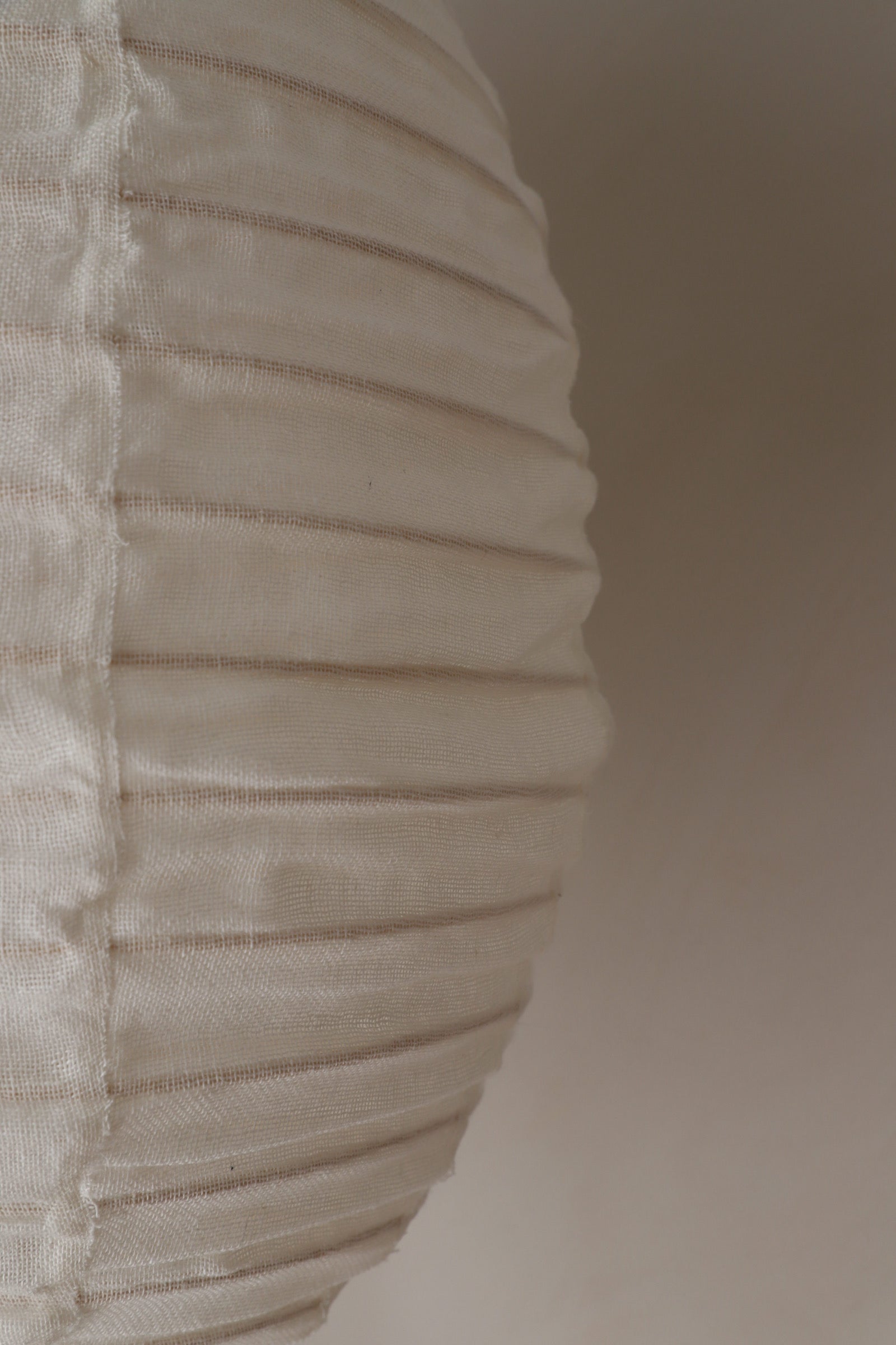 Close-up of a textured warm white fabric surface on a linen pendant light.