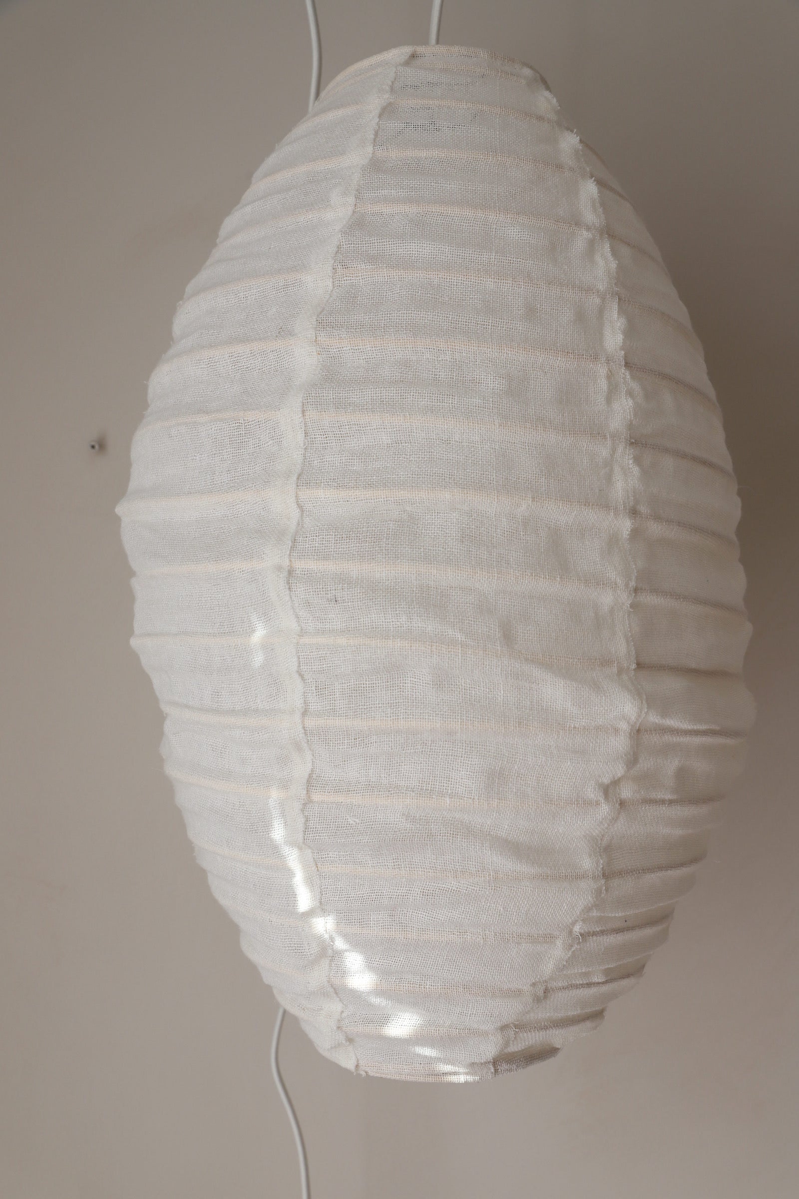 White linen lantern cocoon design, hung swagged next to the bed.