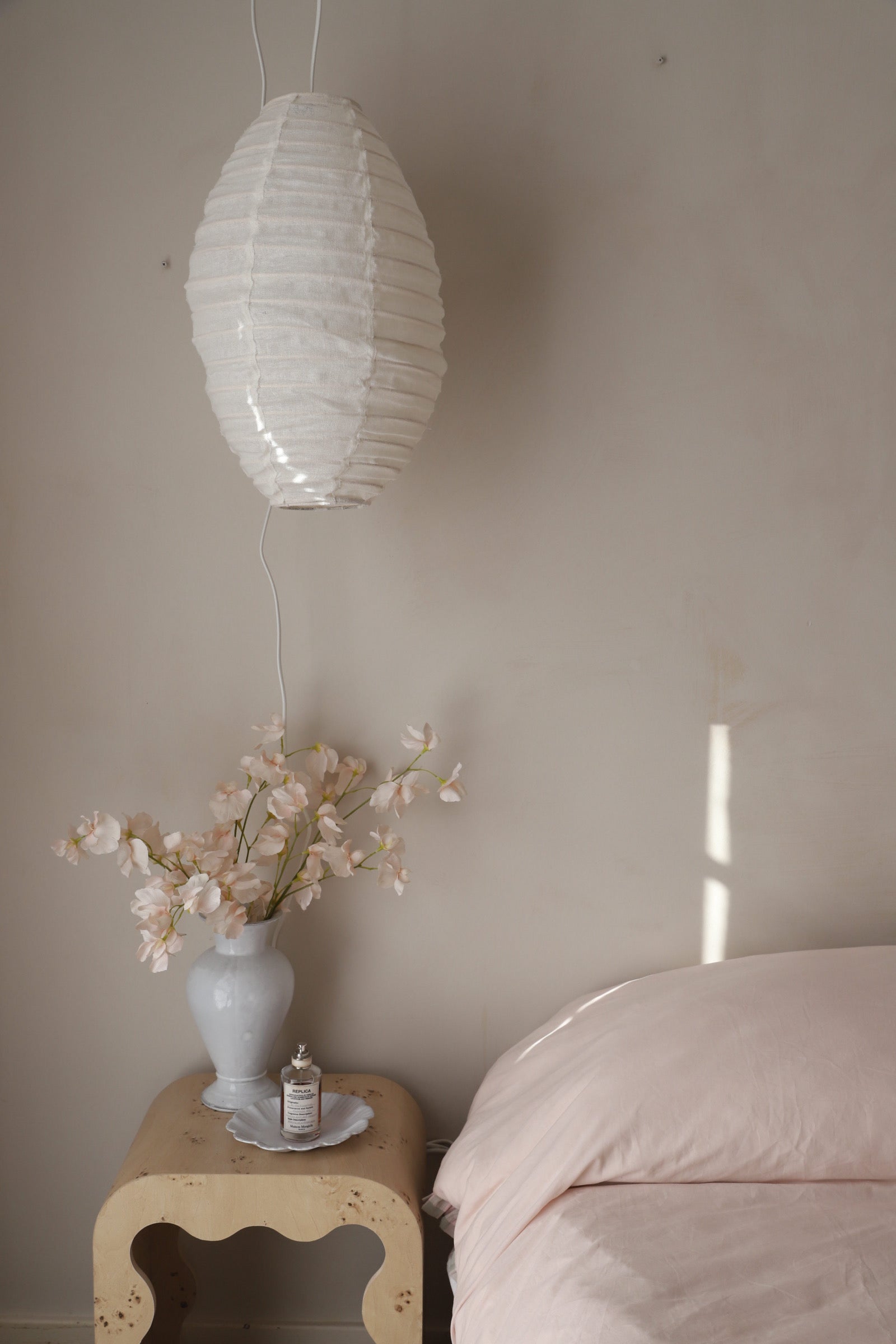 Decorative wall light linen shade next to bed.