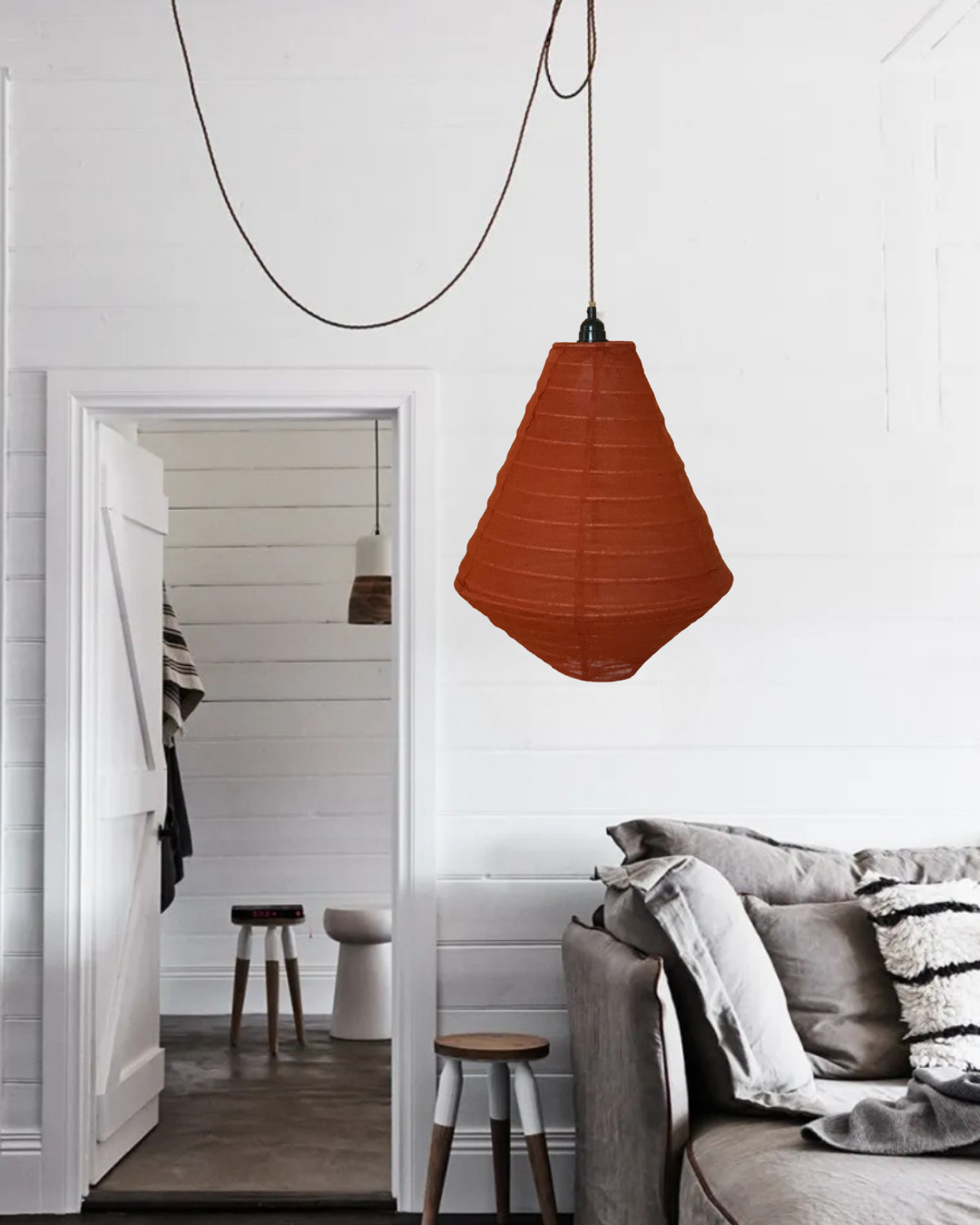 Rust pendant light hanging in a room with a mirror and sofa.