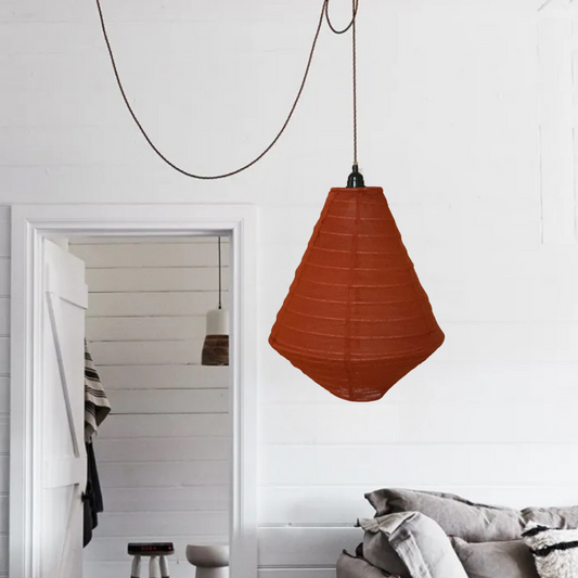 Rust pendant light hanging in a room with a mirror and sofa.
