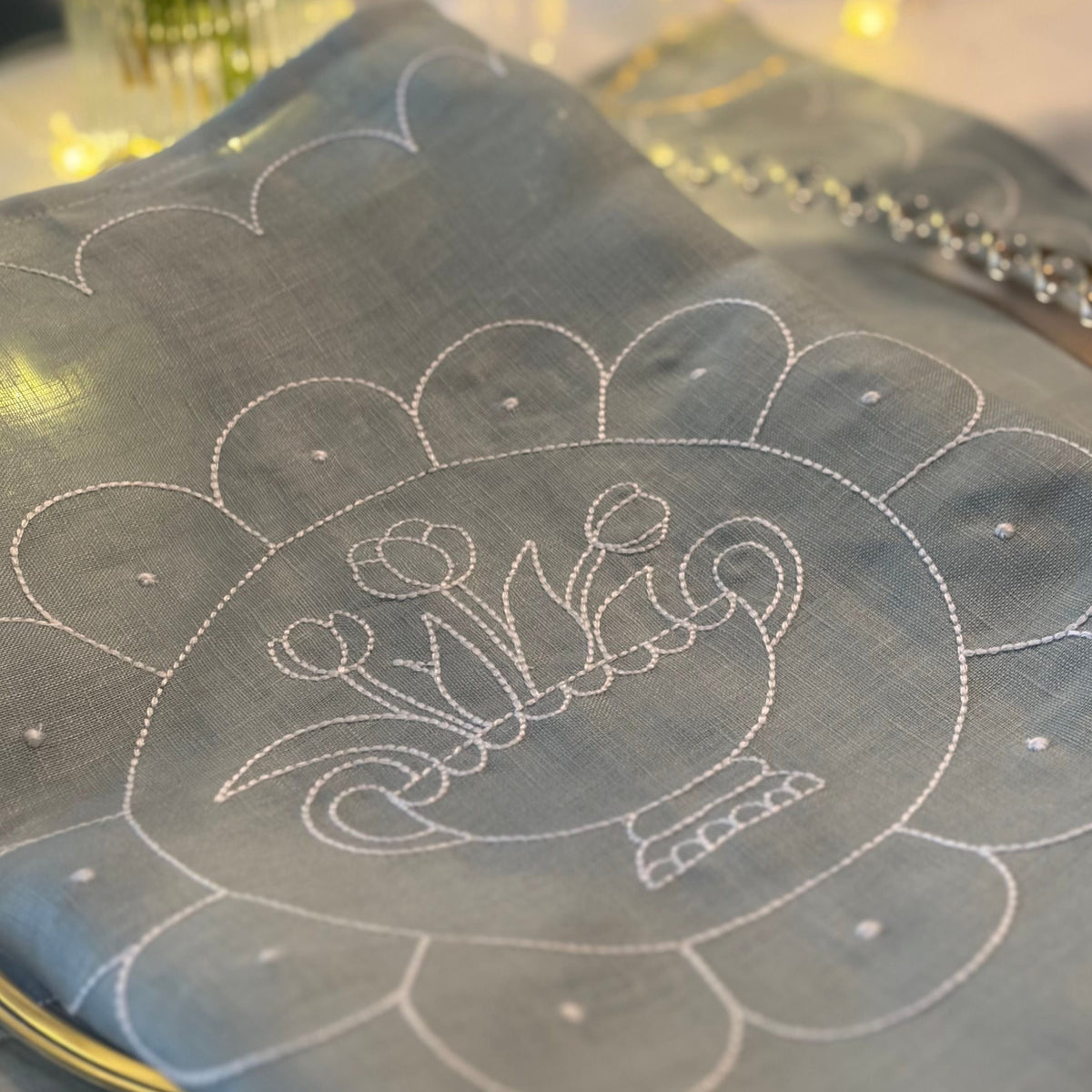 Decorative tablecloth with intricate white embroidery on a table setting.