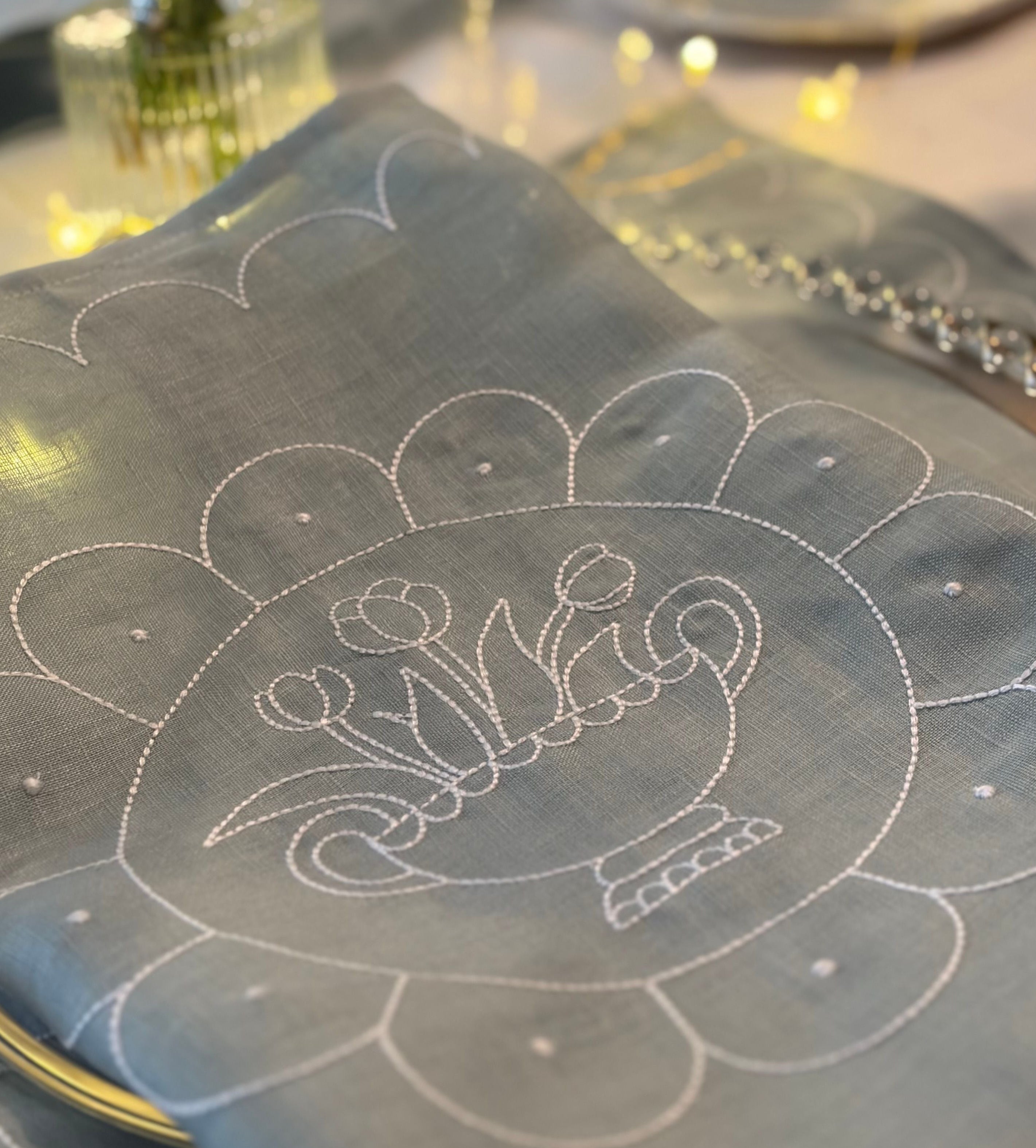 Decorative tablecloth with intricate white embroidery on a table setting.