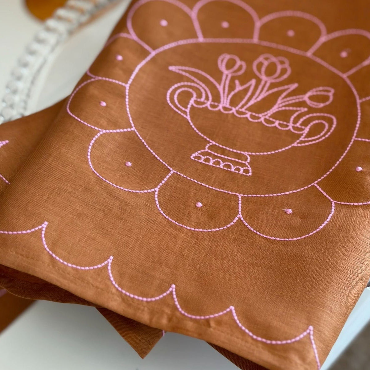 Brown fabric with pink embroidered design on a white surface
