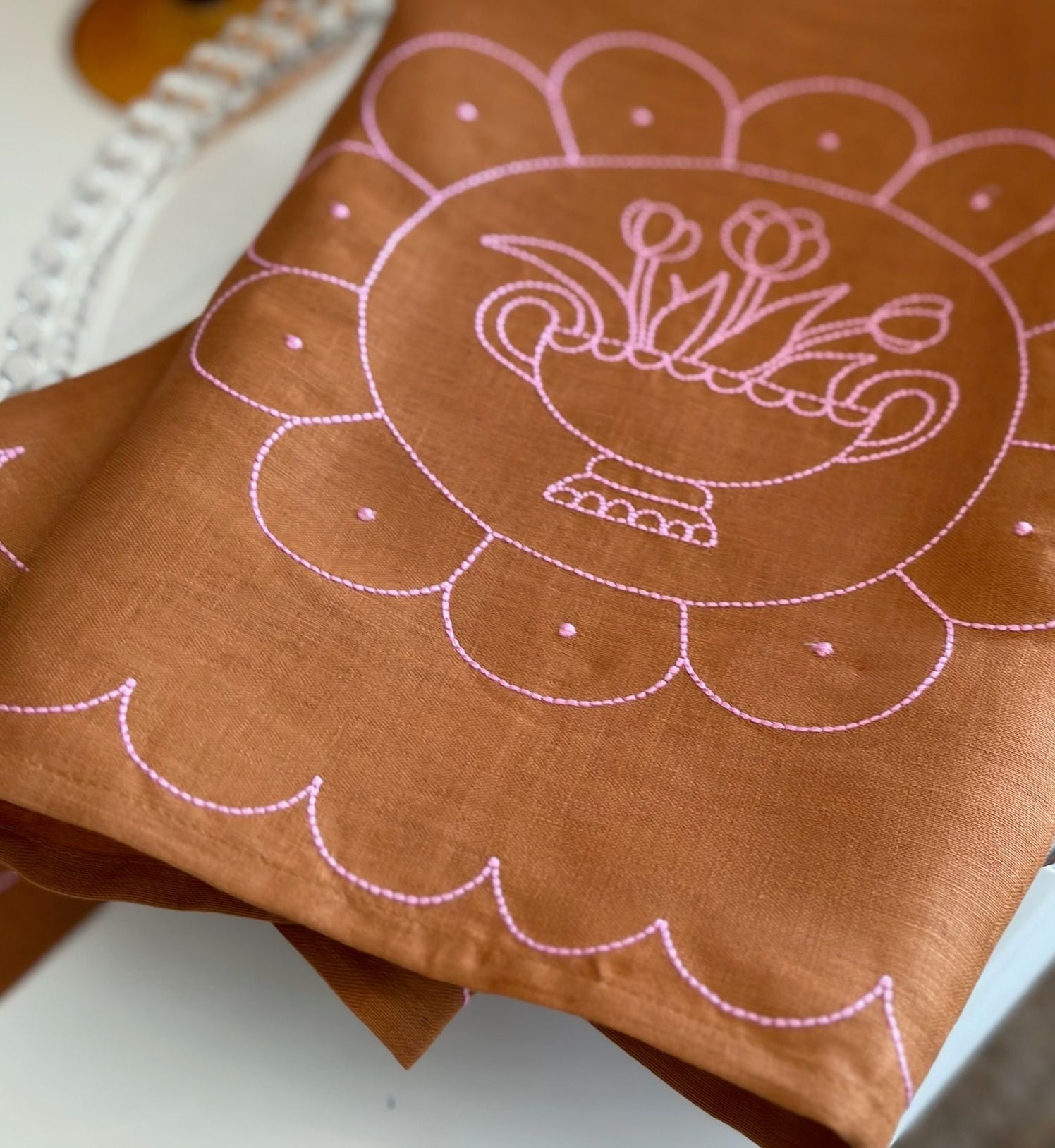 Brown fabric with pink embroidered design on a white surface