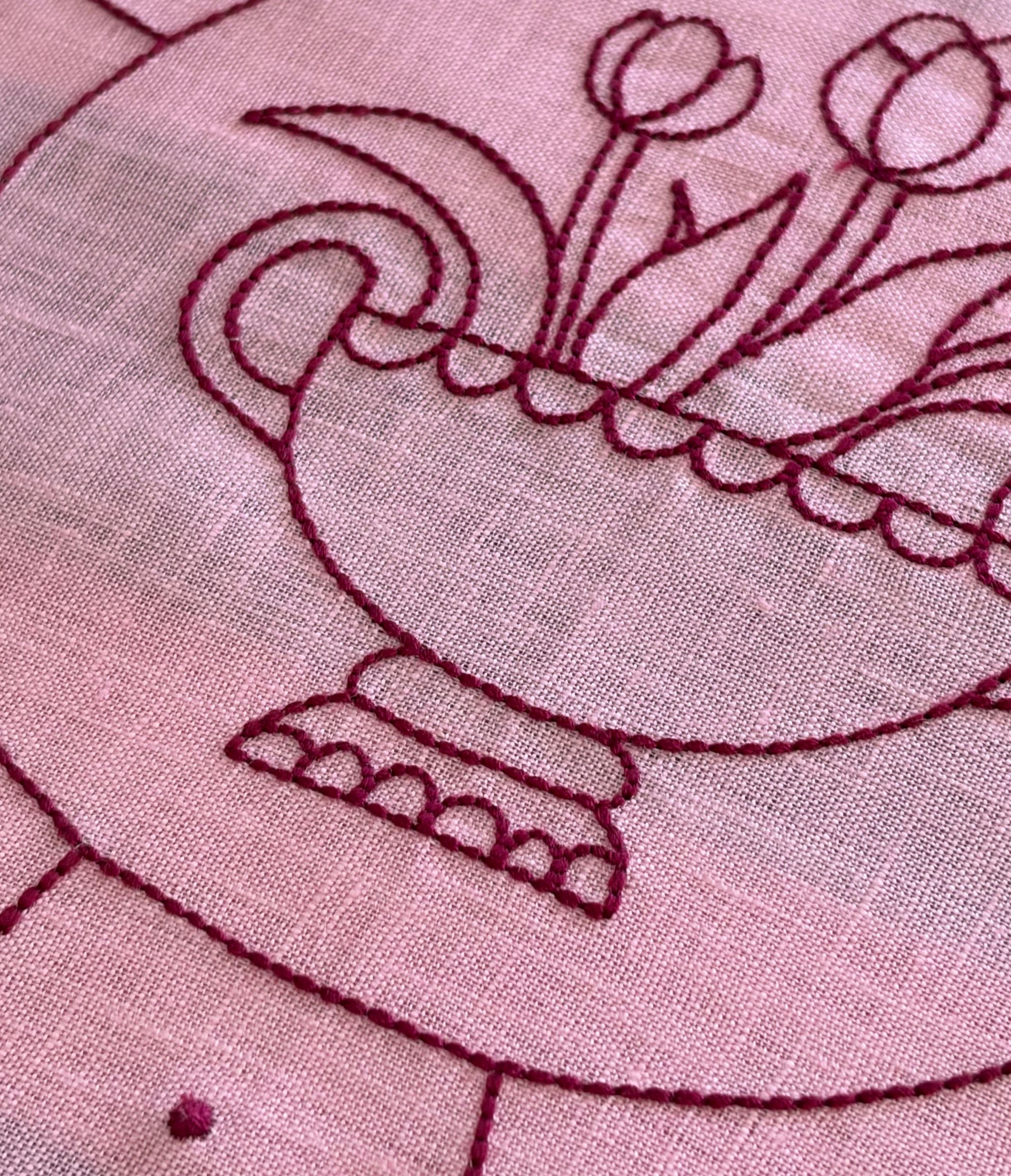 Close-up of embroidered design on fabric with red thread