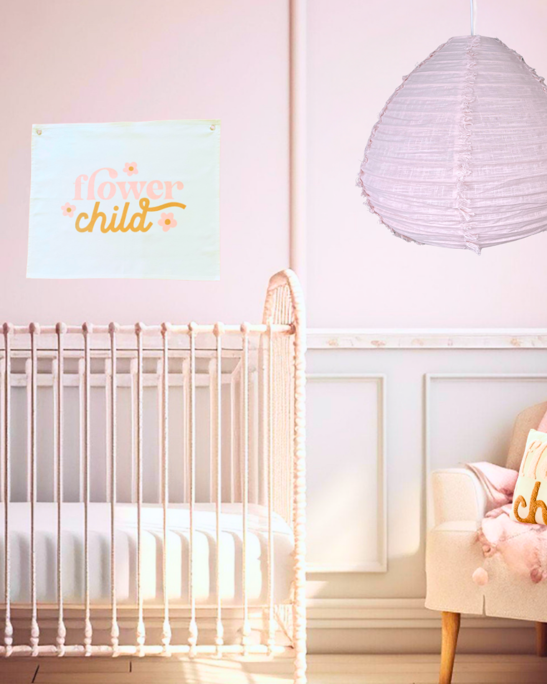 Nursery room with a crib, decorative wall banner, a flower child, and a hanging linen pear-shaped lamp.