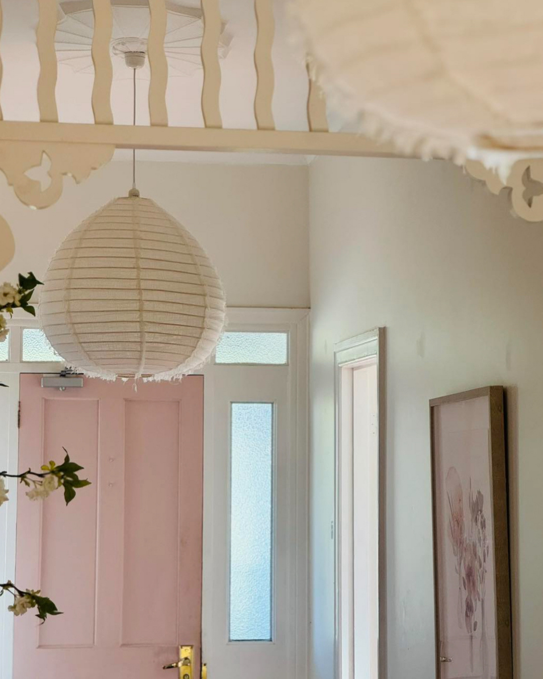 Decorative interior with a pink paere linen lamp shade,  white ceiling, and framed artwork.