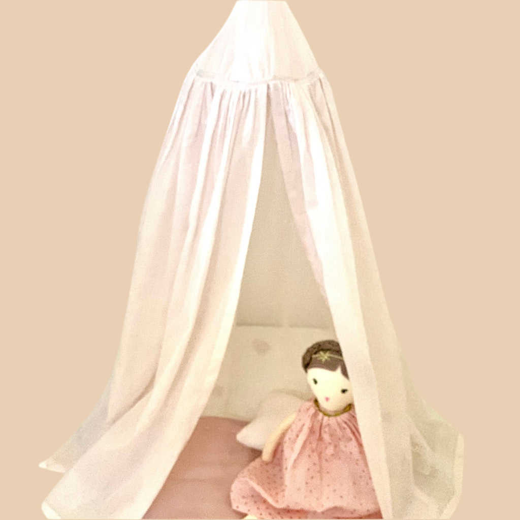Doll in a pink dress under a pinkcanopy on a beige background